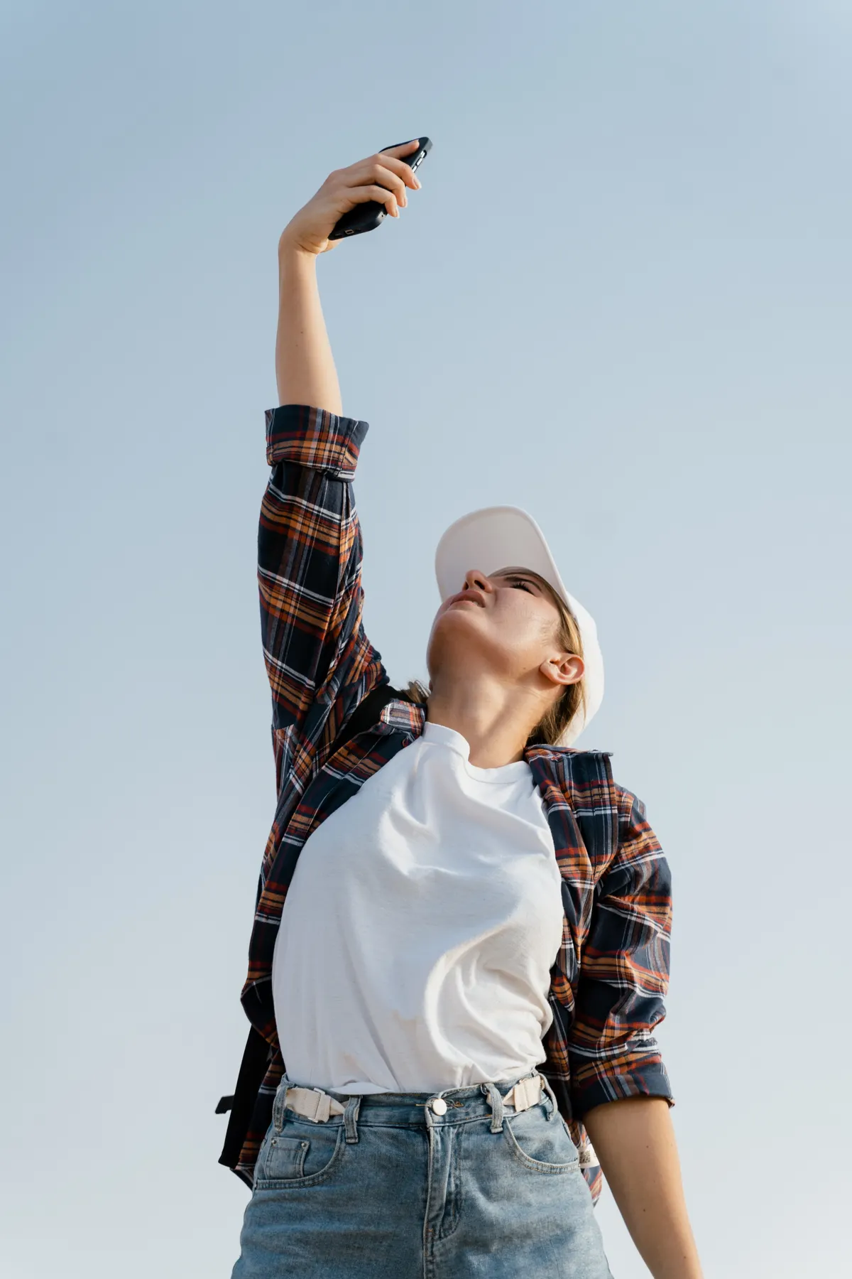 Woman searching for phone signal, symbolising disconnection and worry in a dream about losing a phone.